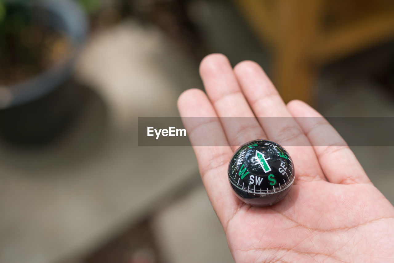 Close-up of person hand holding navigational compass 