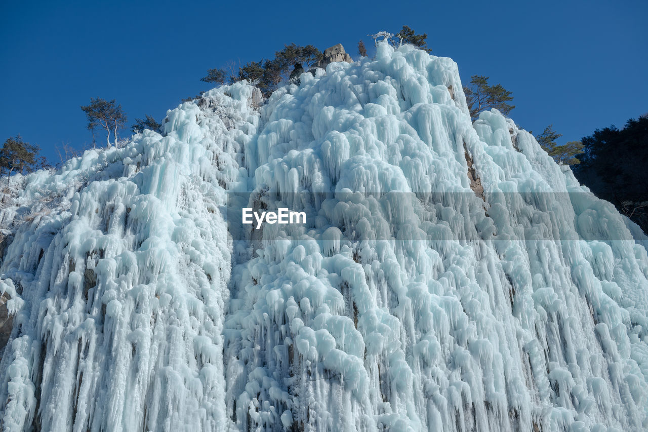 Low angle view of snow against clear blue sky