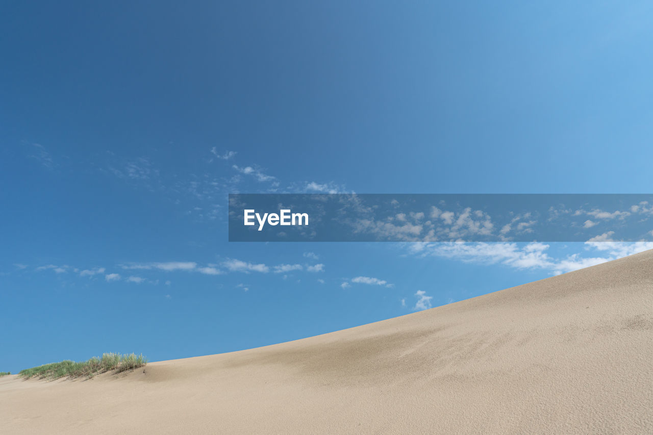 SCENIC VIEW OF SAND DUNE AGAINST SKY