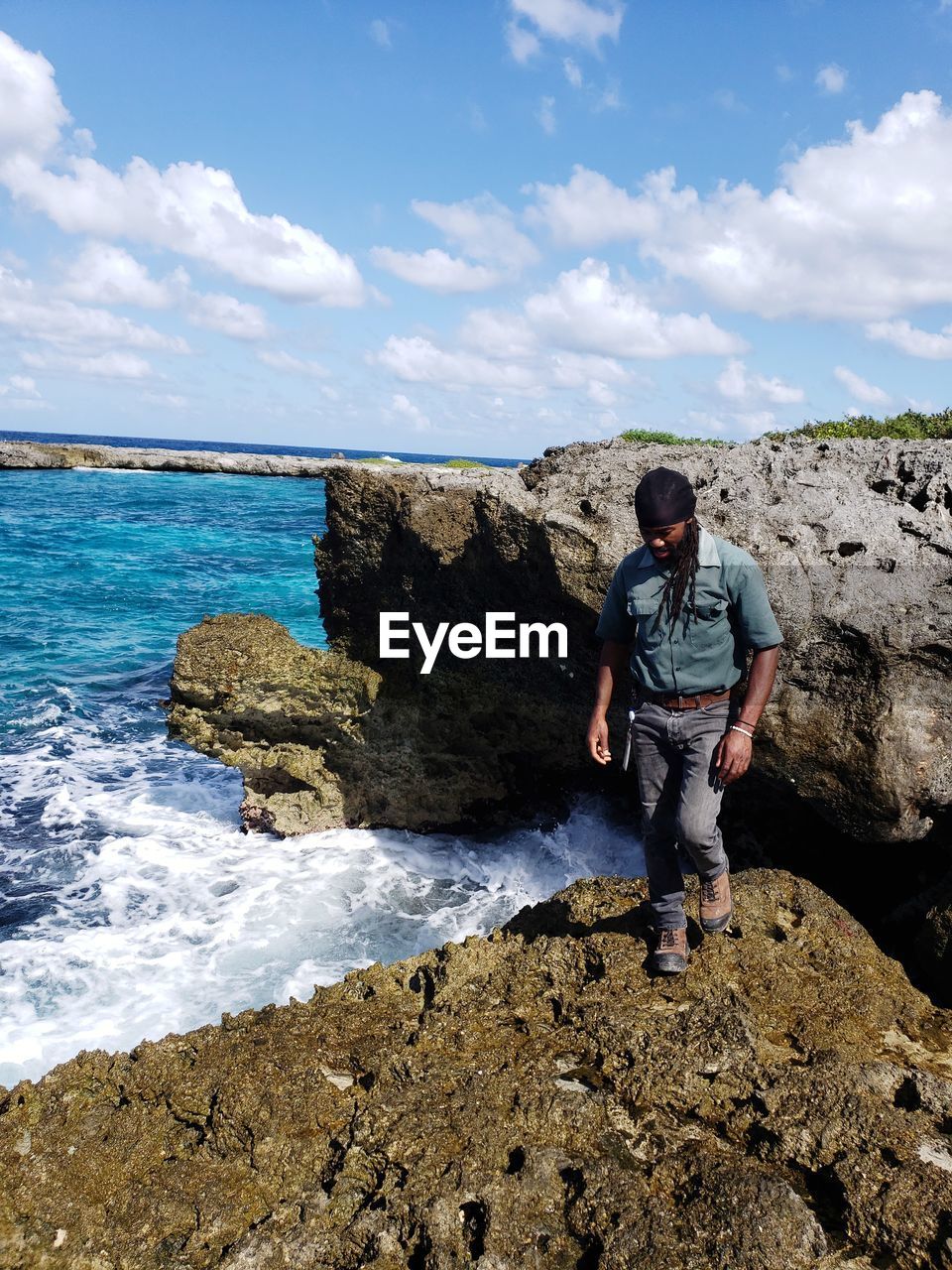 Full length of man walking on rock by sea against sky