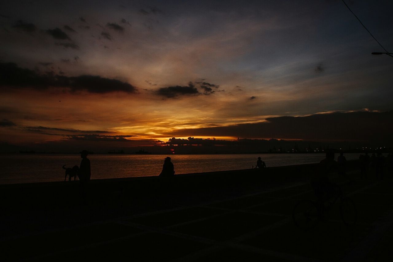 Scenic view of lake against cloudy sky at sunset