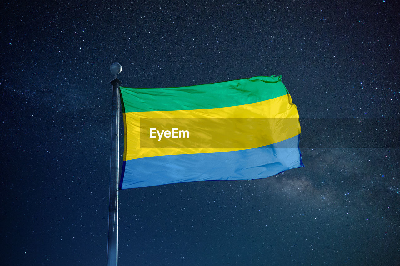 Low angle view of gabon flag against star field sky