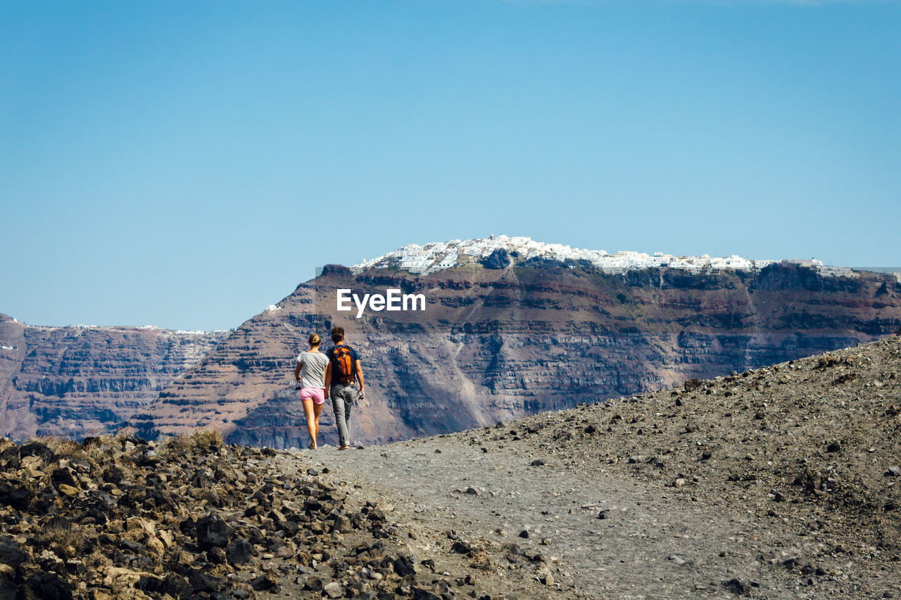 Rear view of man and woman walking against mountain