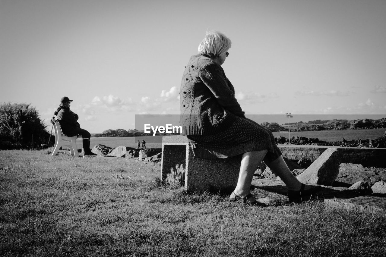 WOMAN STANDING ON GRASSY FIELD