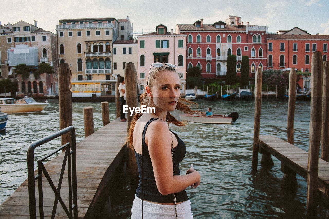 Woman standing on pier by canal