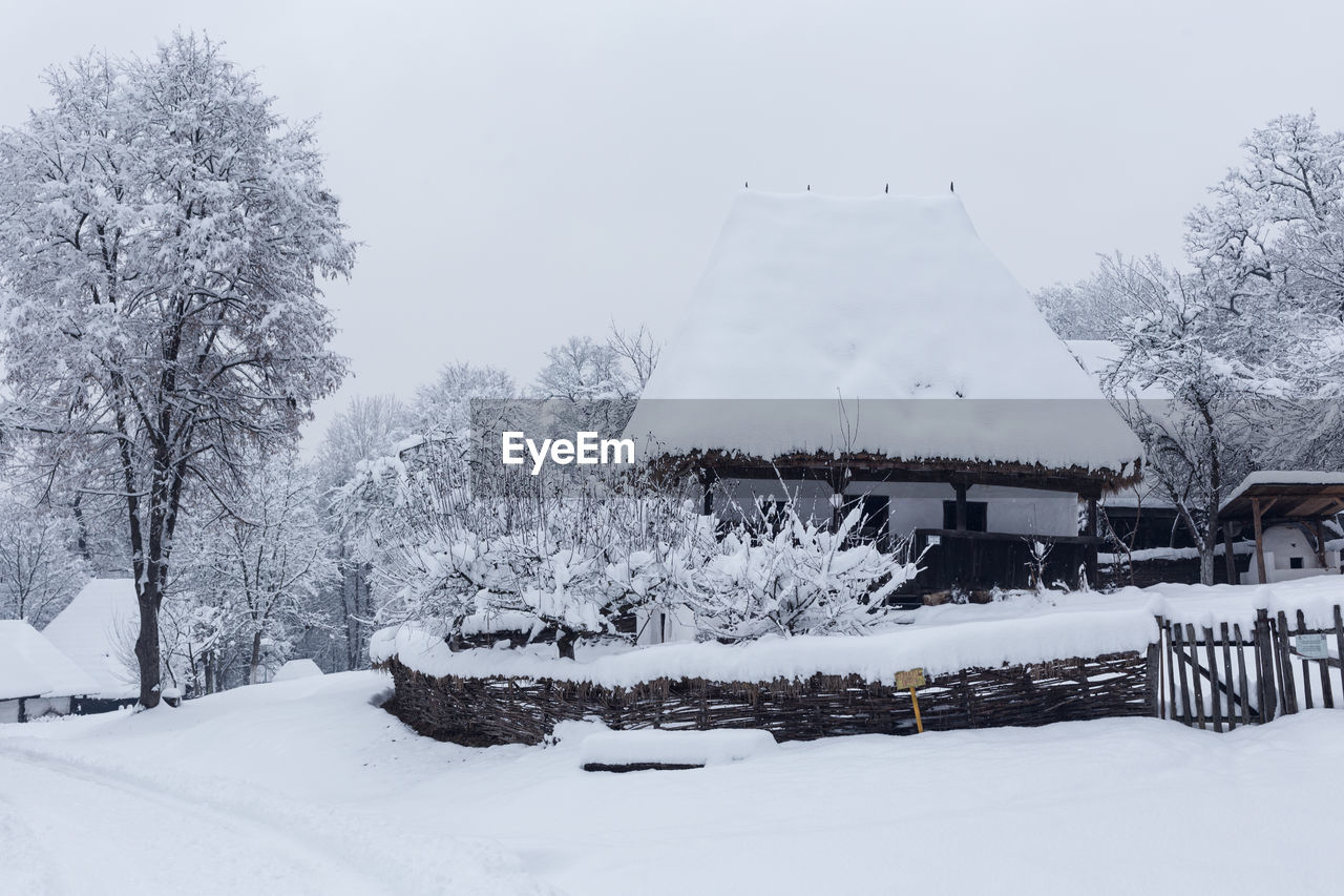 SNOW COVERED FIELD AND BUILDINGS AGAINST SKY