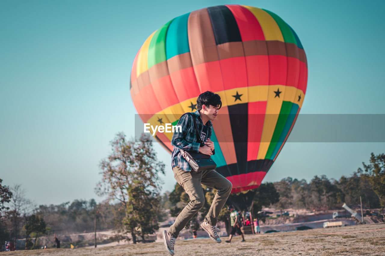 Man levitating against hot air balloon