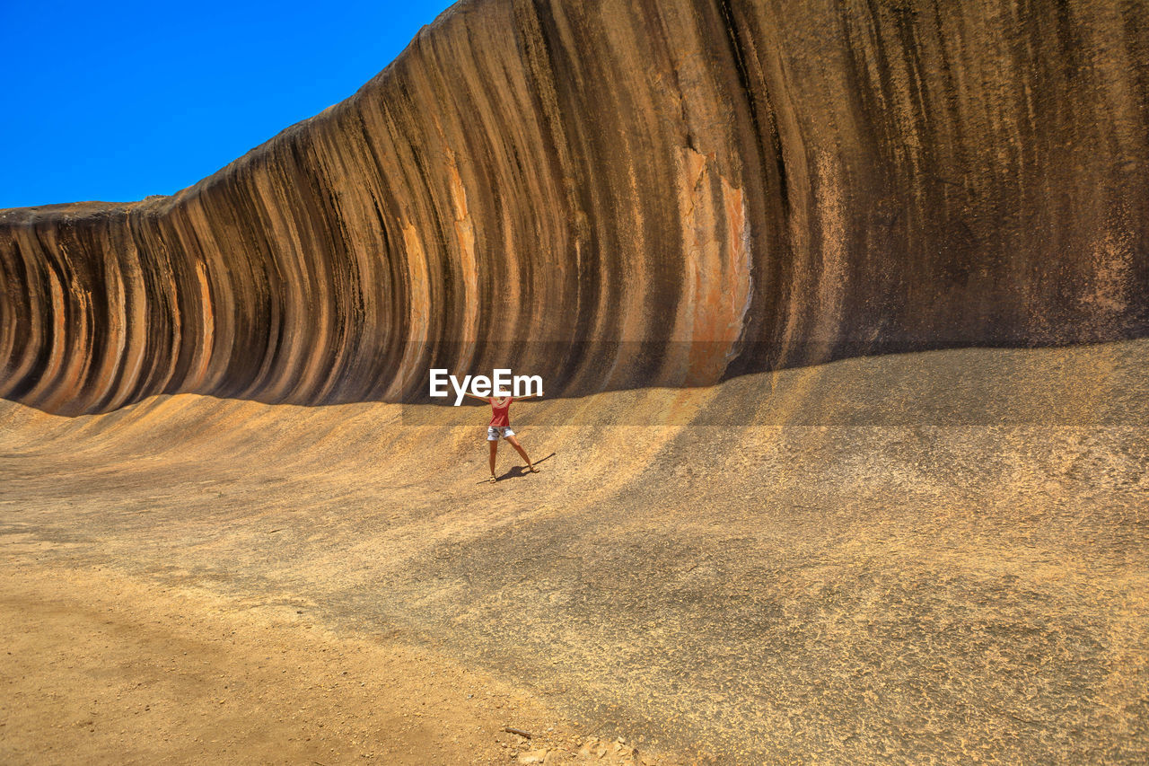 Woman standing with arms outstretched by cliff