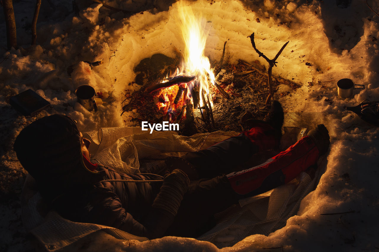 Man sitting by bonfire at night