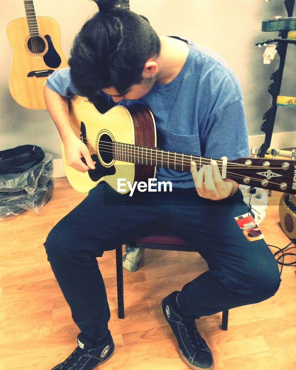 Front view of man playing guitar at home