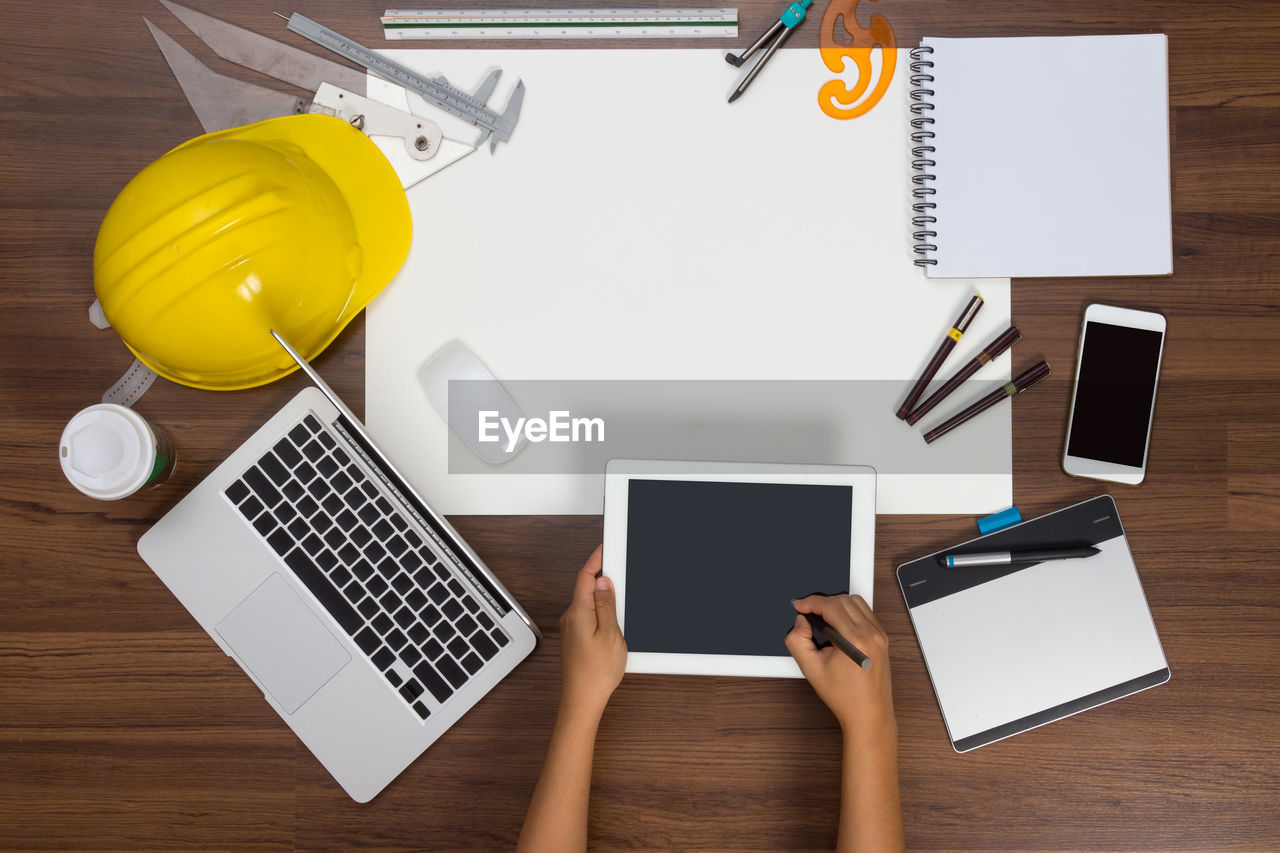 Cropped hands of architect using digital tablet at desk