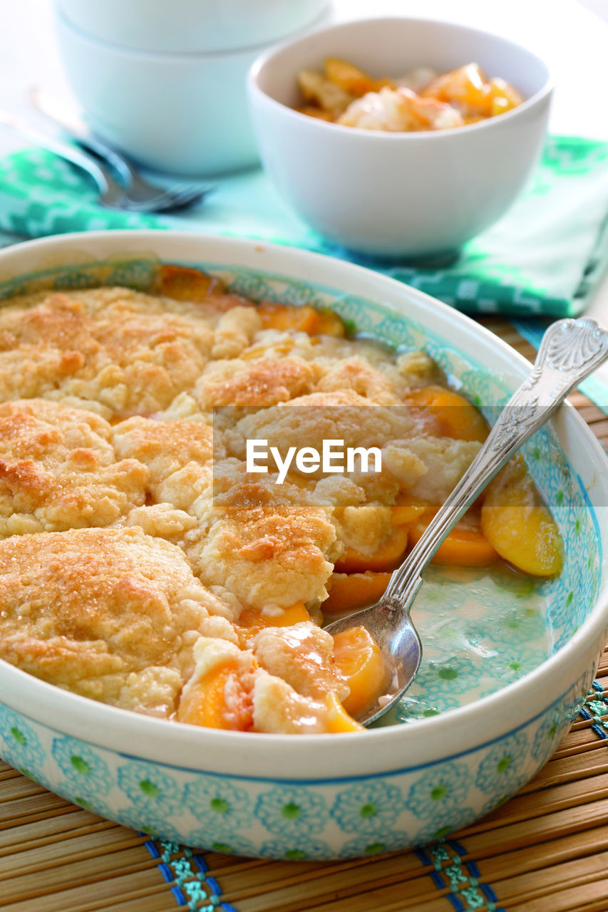 Close-up of baked peach cobbler in casserole on table at home