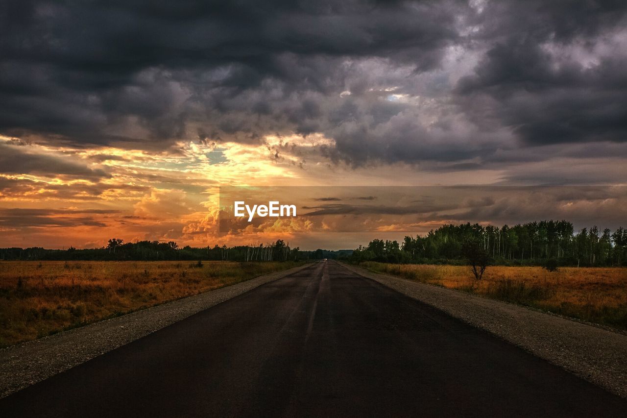 Road by land against sky during sunset