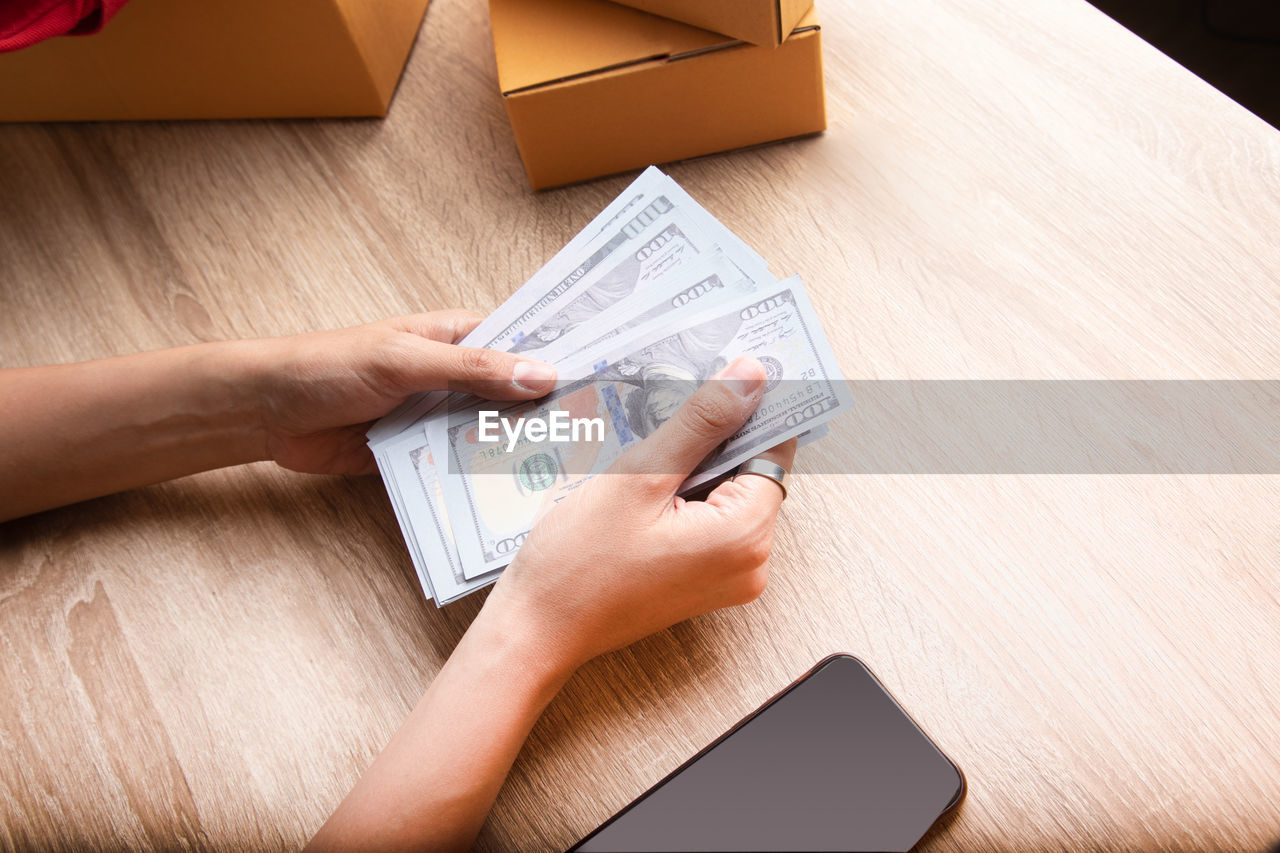 HIGH ANGLE VIEW OF PEOPLE HAND HOLDING TEXT ON TABLE