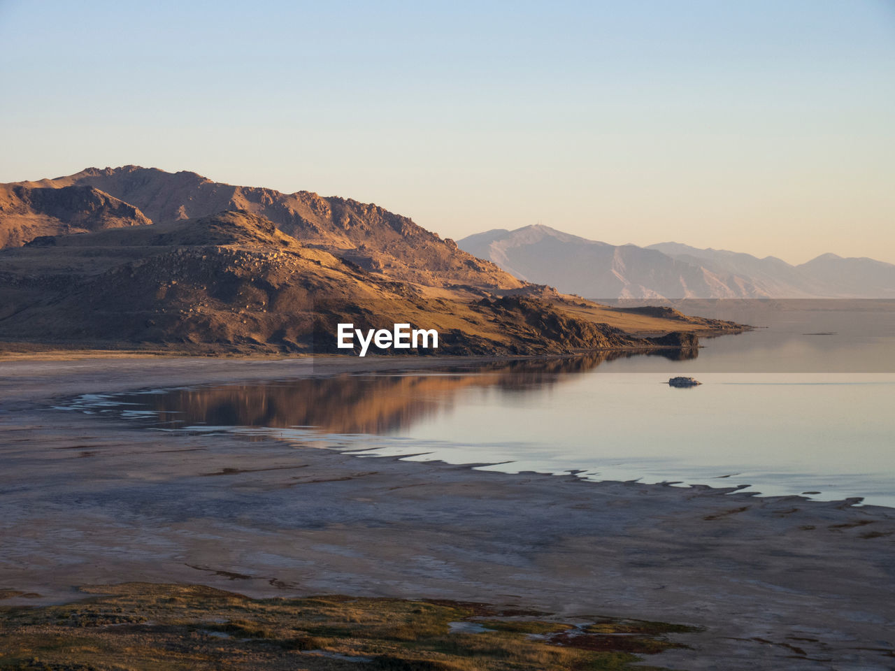 Scenic view of lake by mountains against clear sky