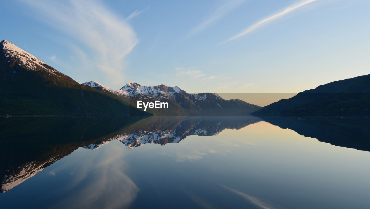 Scenic view of lake by mountains against sky