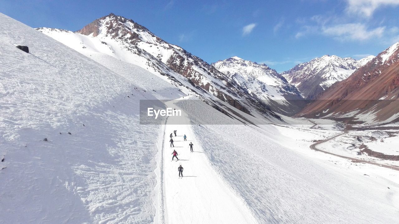 People skiing by snowcapped mountains