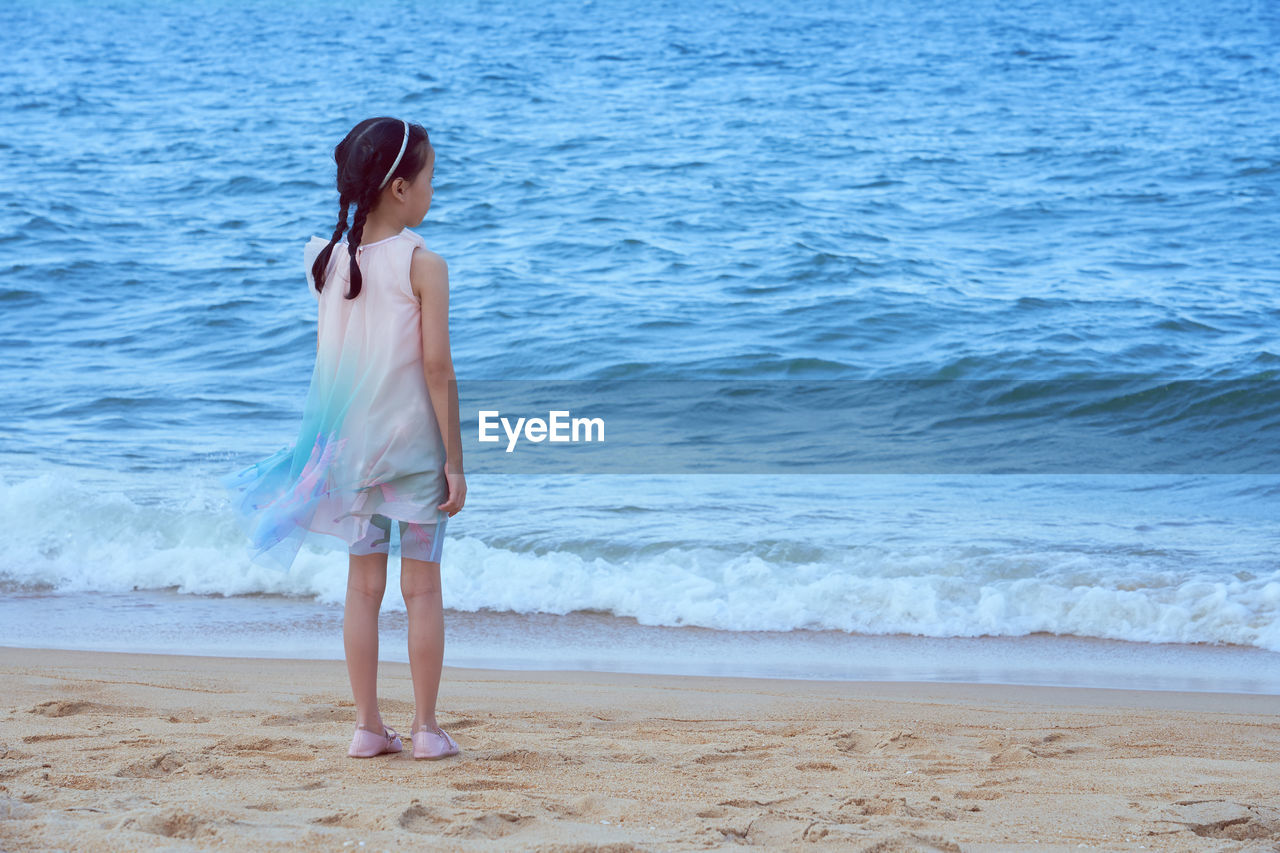 REAR VIEW OF WOMAN STANDING ON SHORE