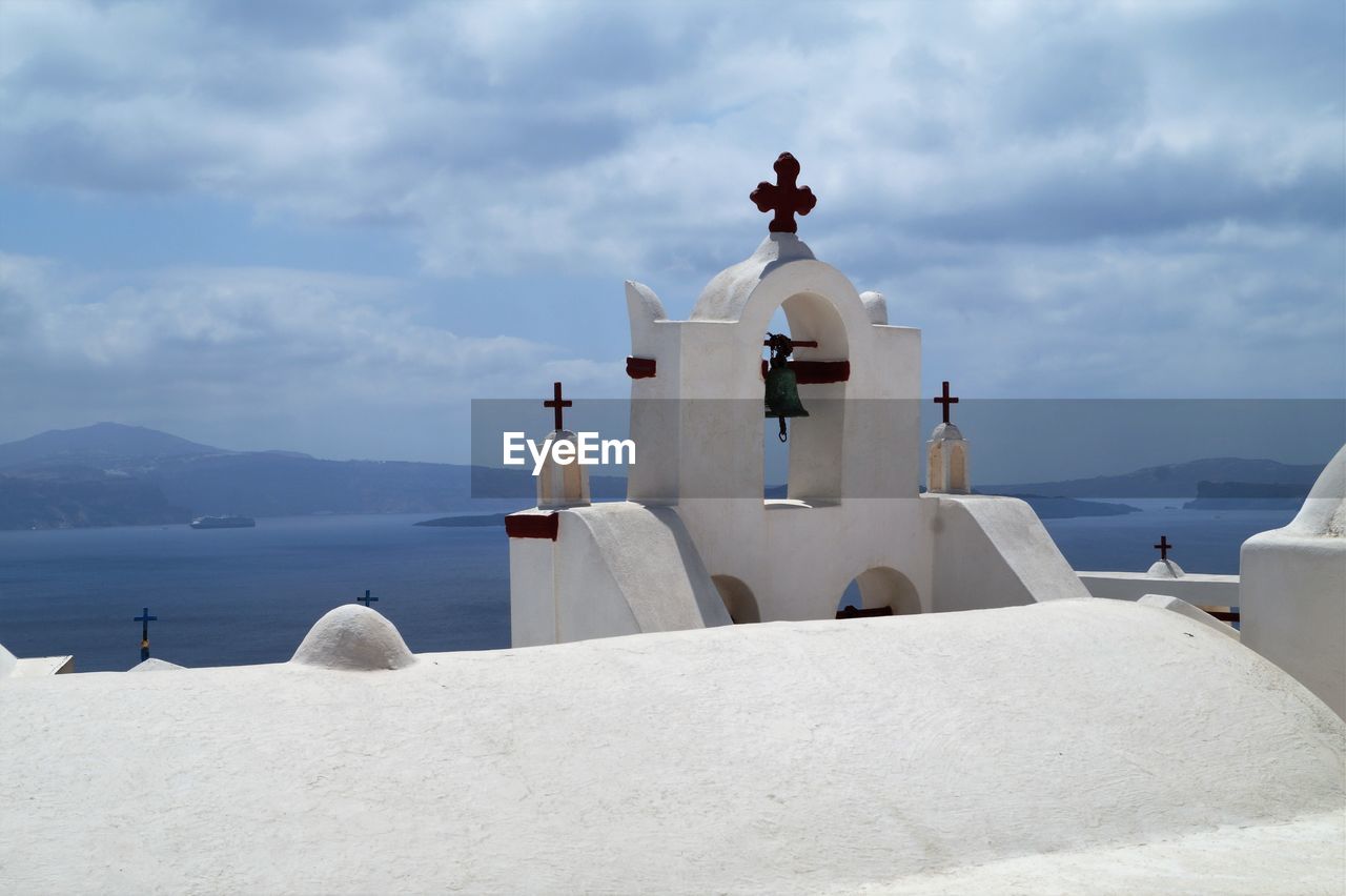 White church by sea against sky