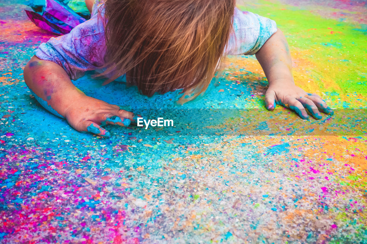 Girl playing with multi colored powder paint