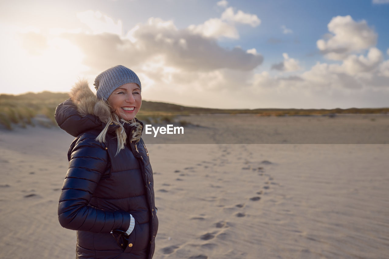 Portrait of smiling young woman standing on beach