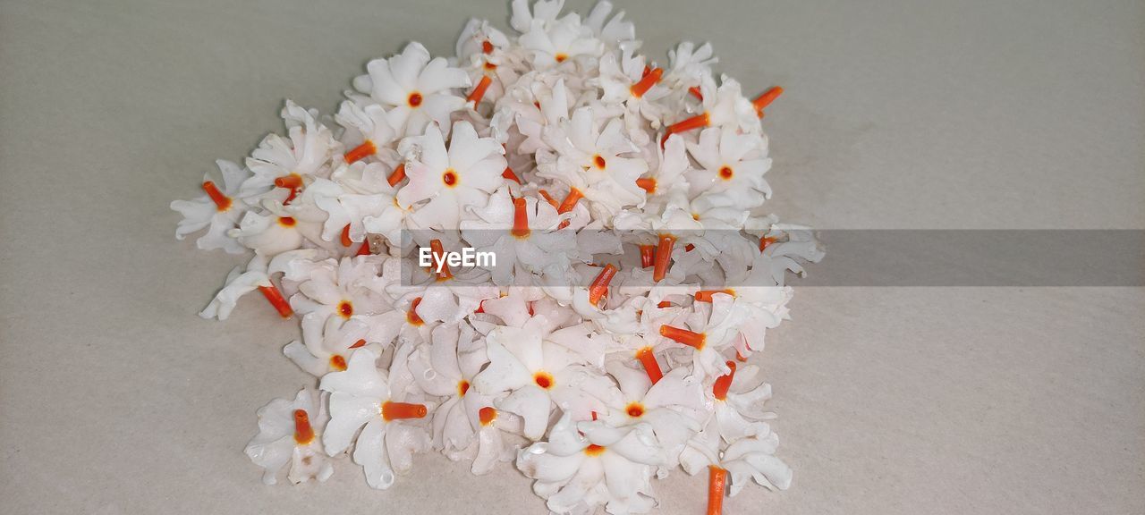 HIGH ANGLE VIEW OF MULTI COLORED FLOWERS ON TABLE AGAINST GRAY BACKGROUND