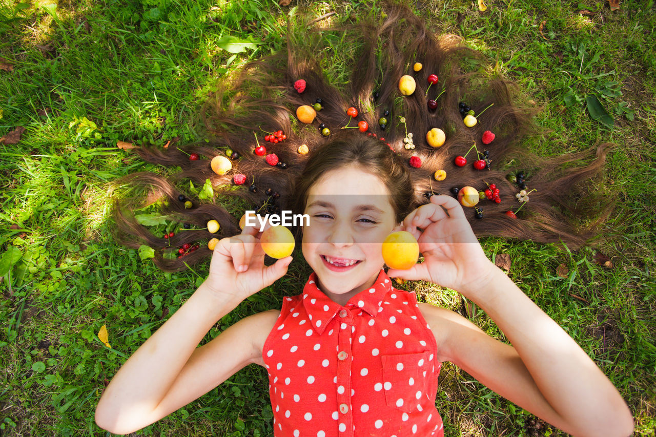 PORTRAIT OF A SMILING YOUNG WOMAN HOLDING APPLES