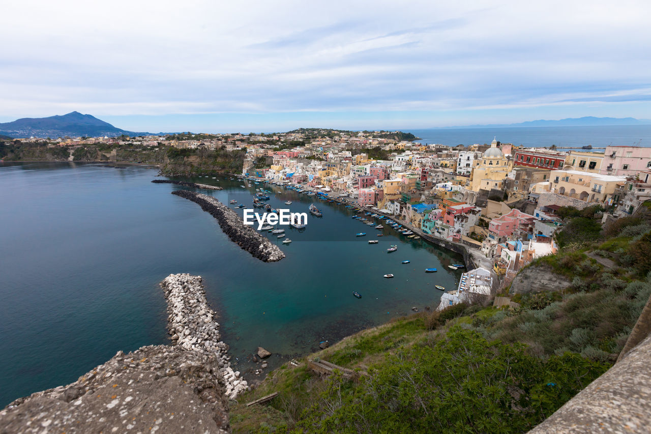 High angle view of sea by buildings against cloudy sky