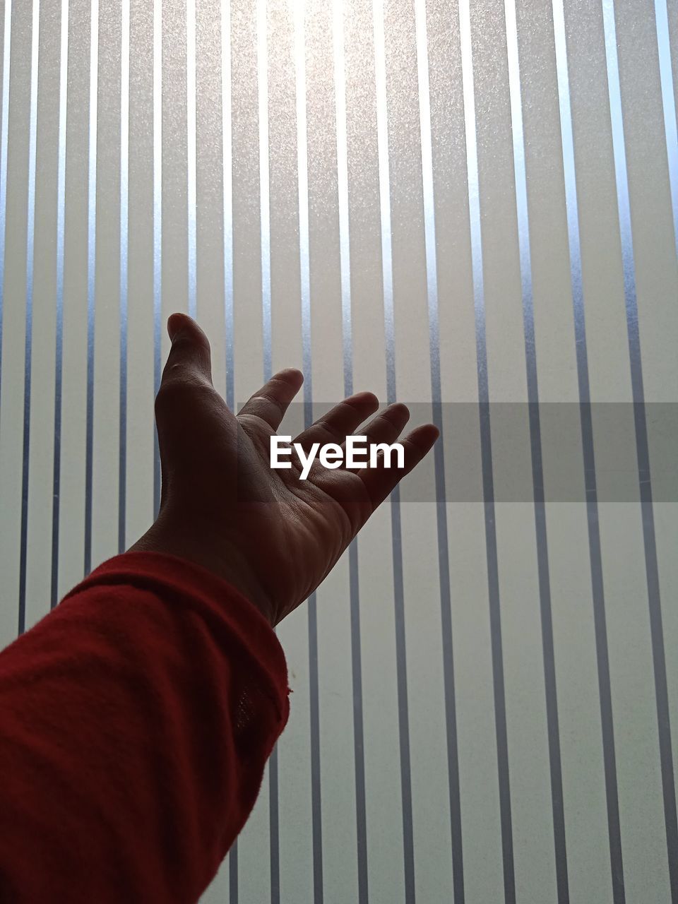 MIDSECTION OF PERSON WITH HAND ON METAL CURTAIN