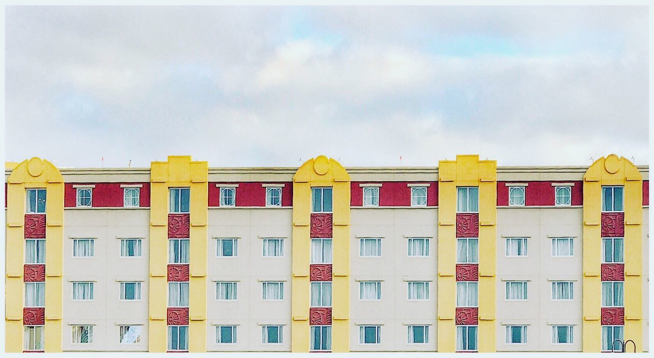MULTI COLORED BUILDING AGAINST CLOUDY SKY