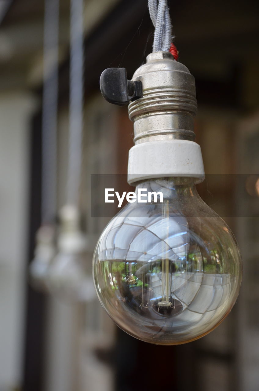 CLOSE-UP OF LIGHT BULB HANGING FROM GLASS
