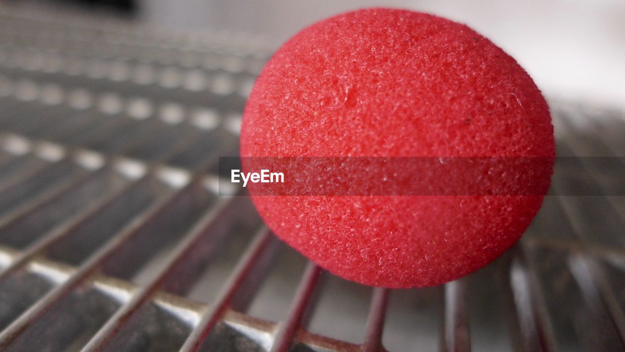 Close-up of red clown on metal grate