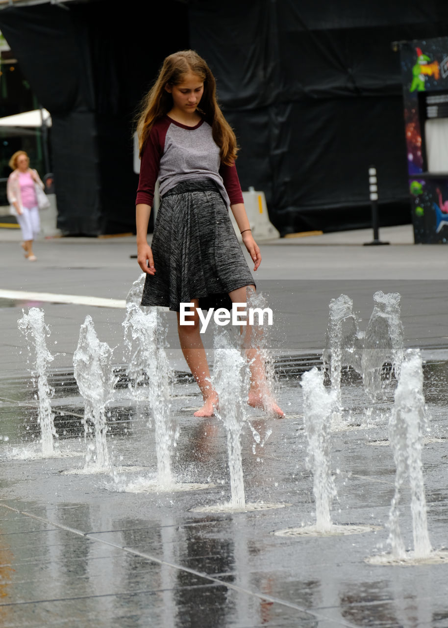 FULL LENGTH PORTRAIT OF A GIRL SPLASHING WATER