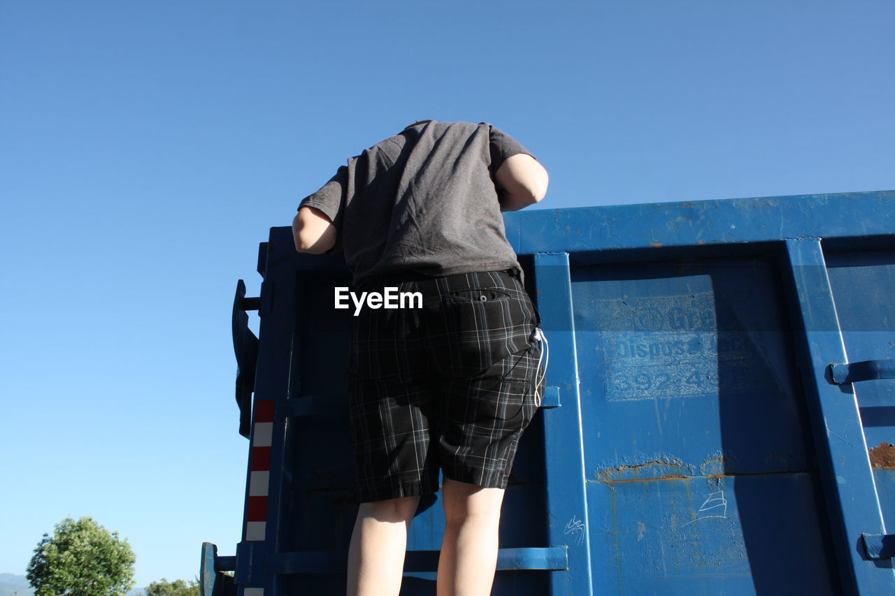Low angle view of man on dumpster