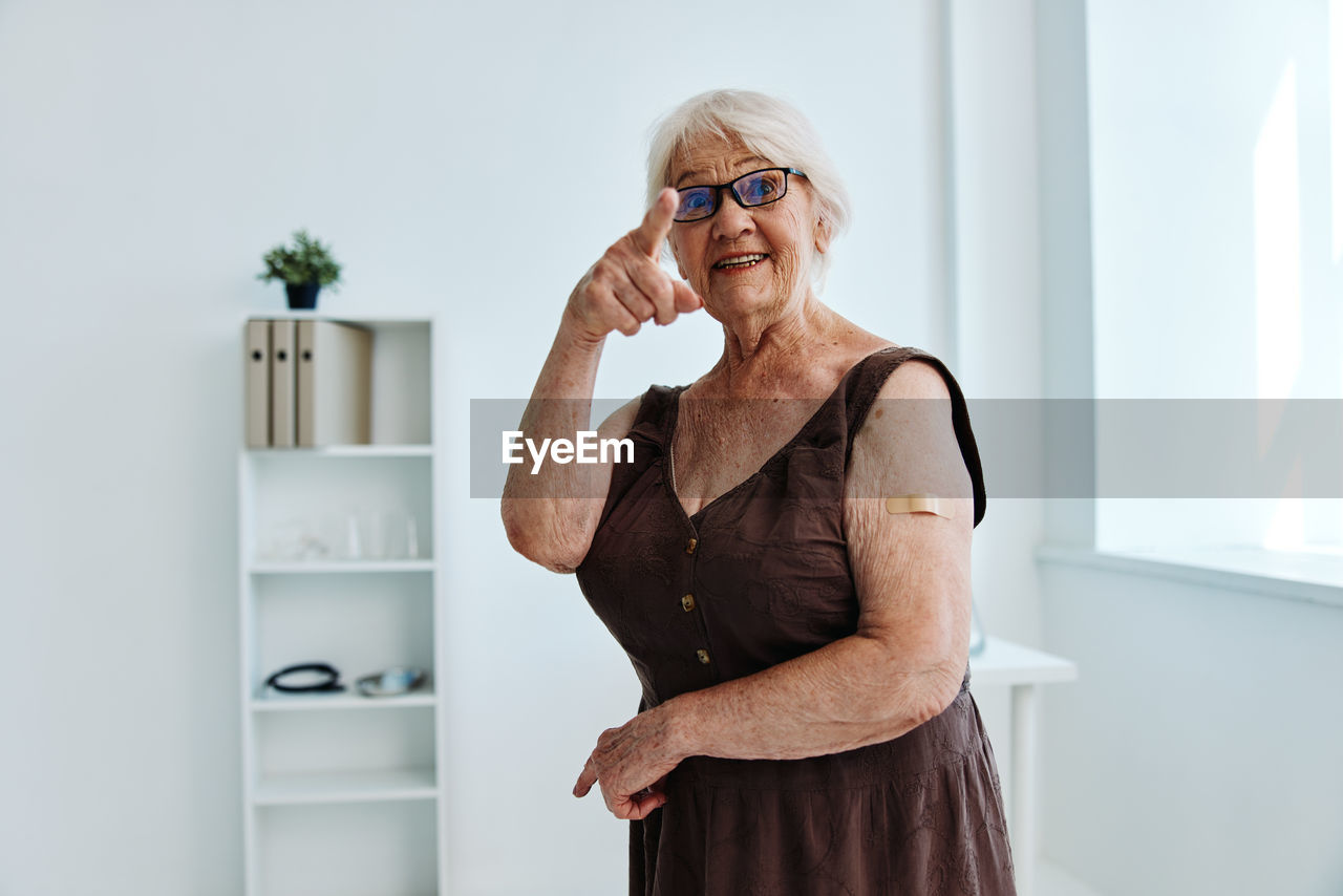 Portrait of senior woman gesturing while standing at hospital