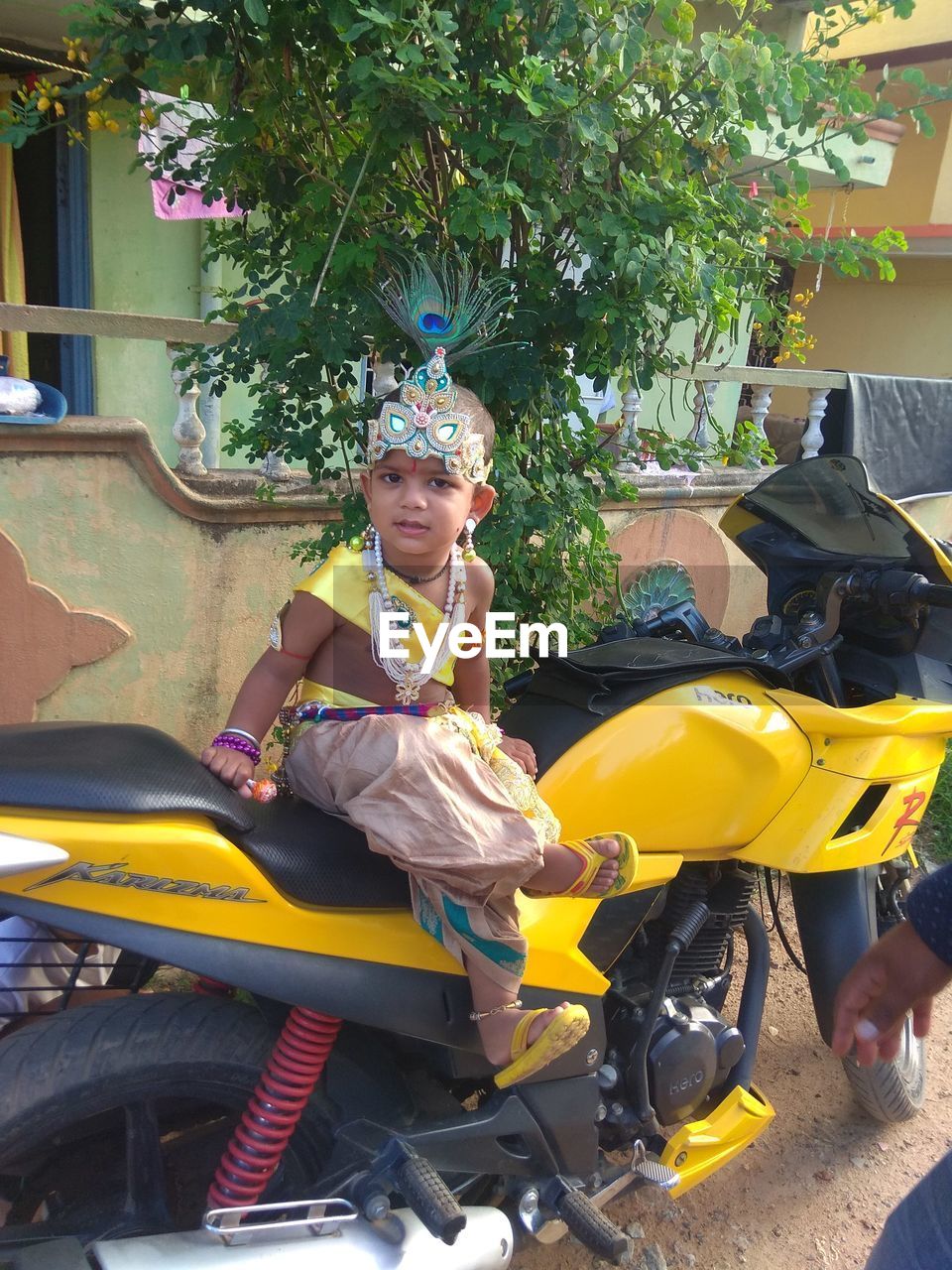 CUTE GIRL SITTING IN TRADITIONAL CLOTHING OUTDOORS