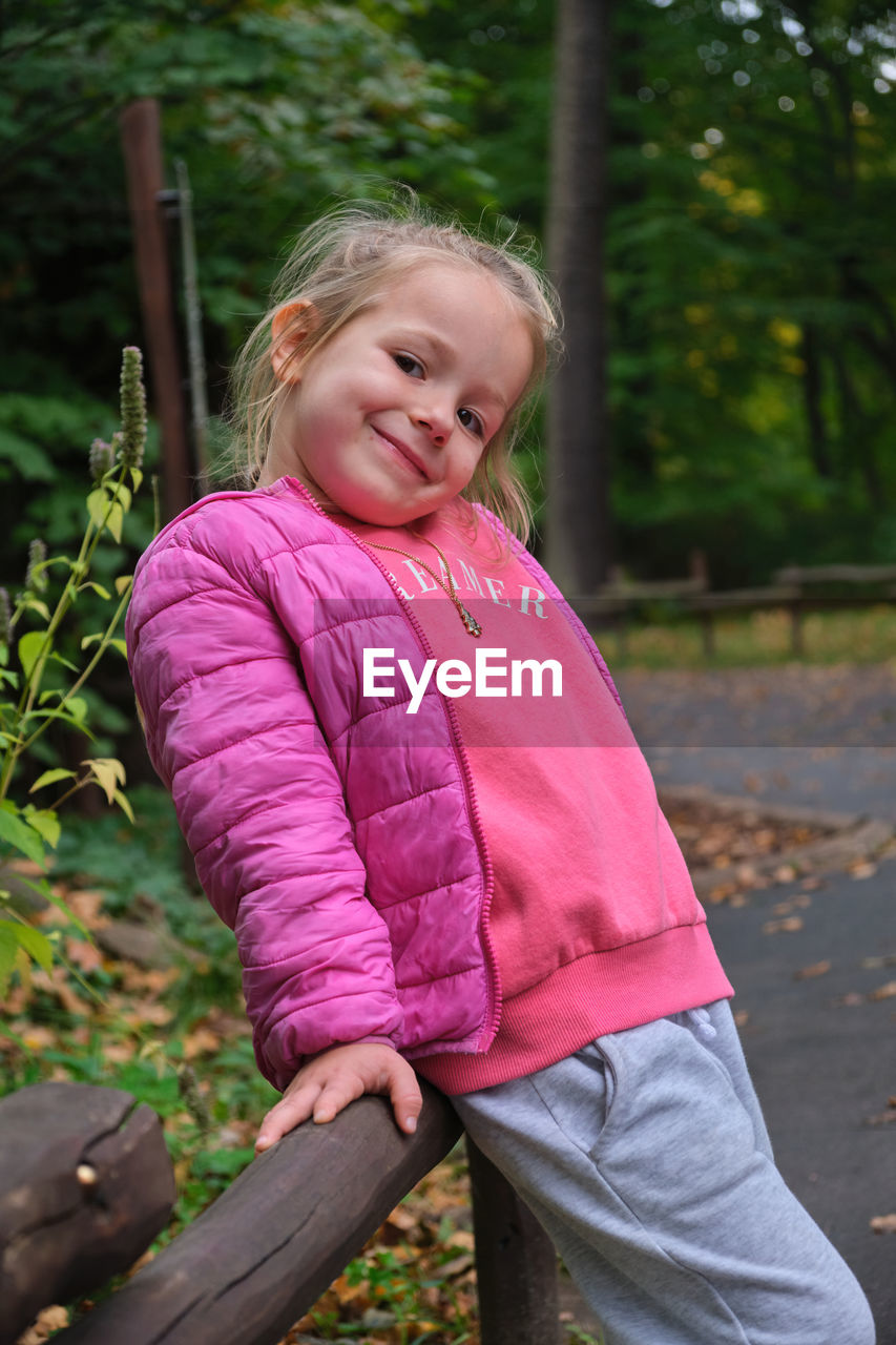 childhood, child, one person, female, smiling, women, pink, portrait, spring, emotion, happiness, casual clothing, blond hair, leisure activity, person, cute, looking at camera, nature, innocence, day, portrait photography, three quarter length, toddler, lifestyles, outdoors, tree, plant, front view, clothing, hairstyle, standing, cheerful, autumn, enjoyment, full length, teeth, human face, smile, sitting, fun