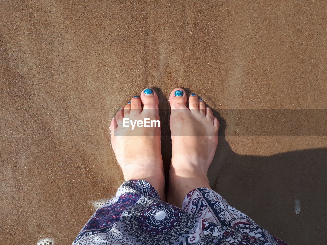 Low section of woman standing at beach