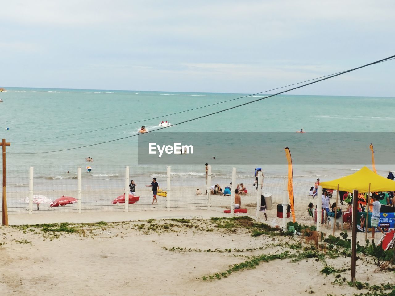 PANORAMIC VIEW OF PEOPLE ON BEACH AGAINST SKY