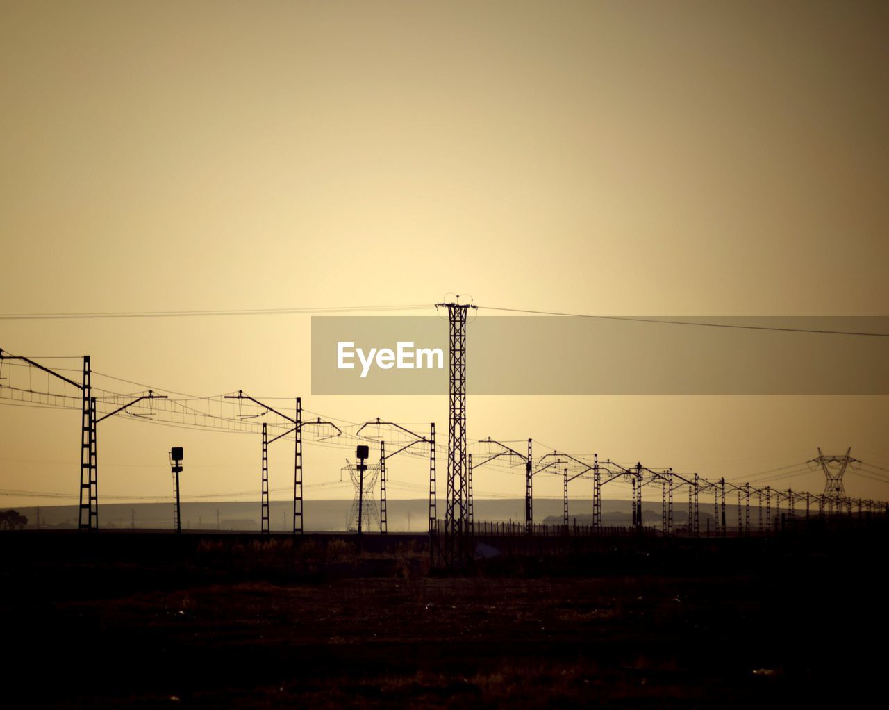 SILHOUETTE ELECTRICITY PYLONS AGAINST CLEAR SKY