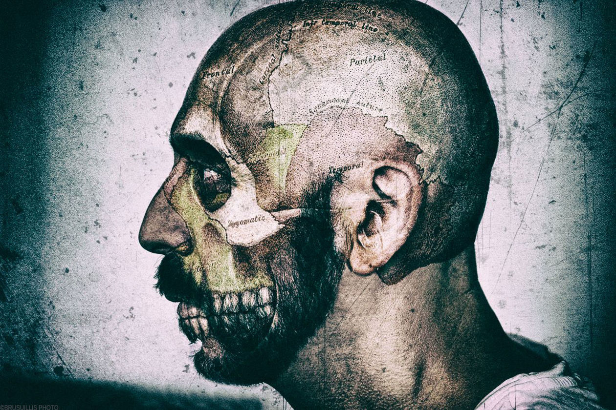 Double exposure image of animal skull and man against wall