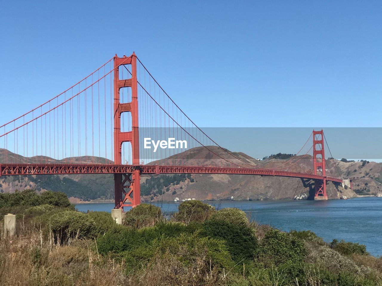 Suspension bridge over river against blue sky