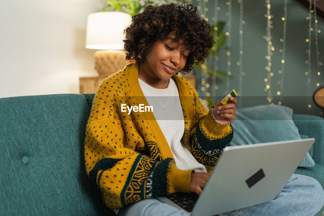 young woman using digital tablet while sitting on sofa at home