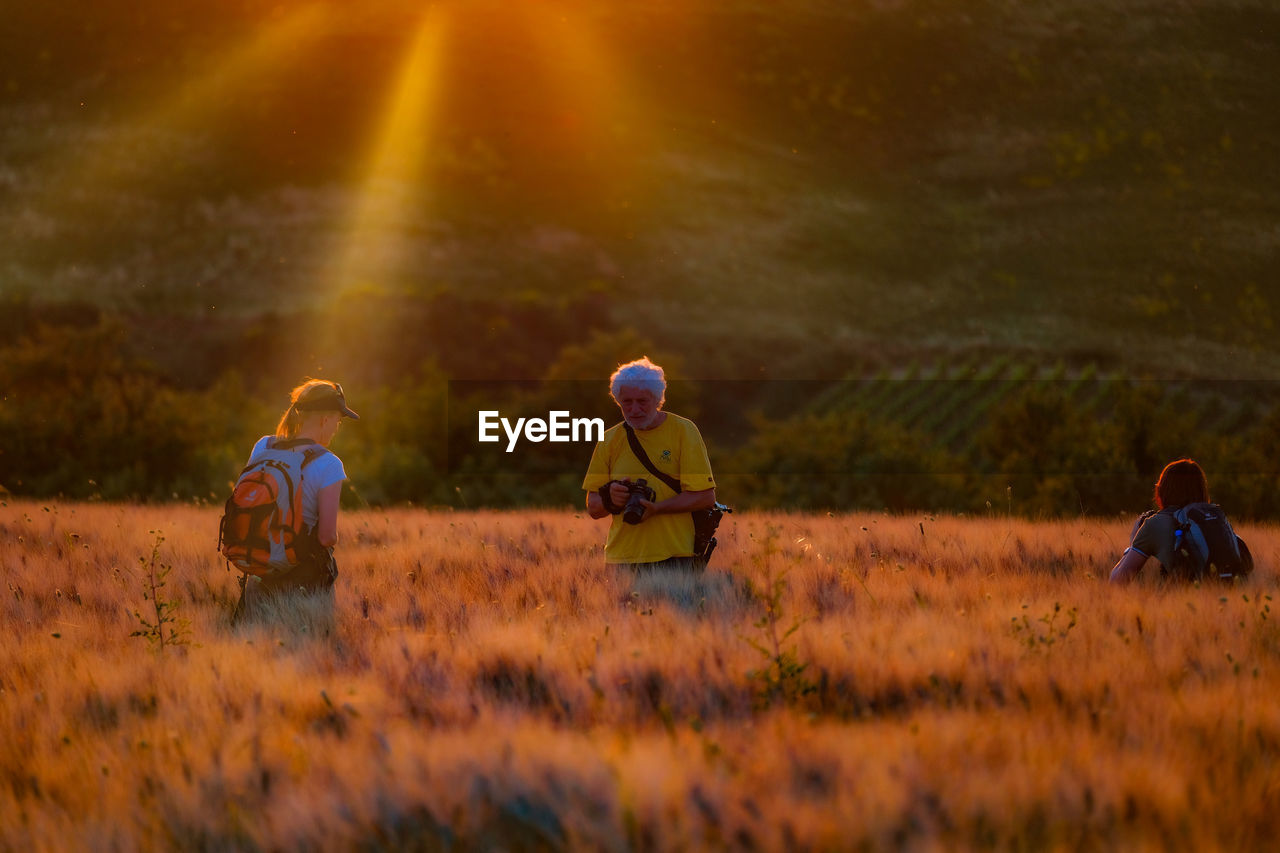 MAN AND WOMAN ON FIELD DURING SUNRISE