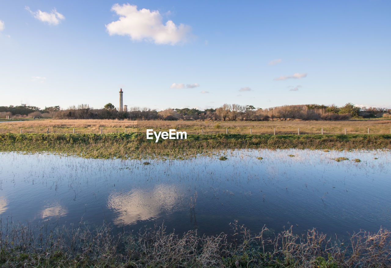 Scenic view of lake and lighthouse against sky