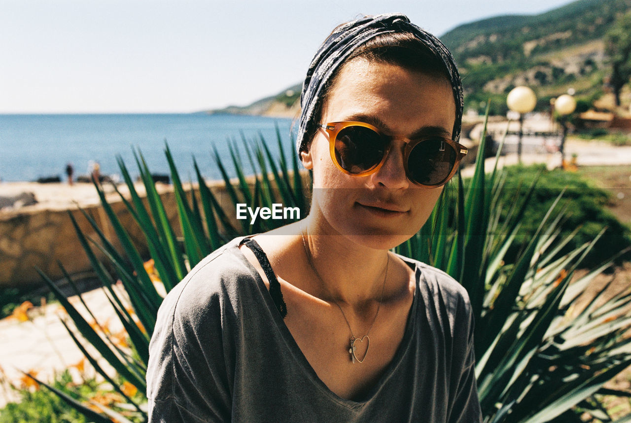 Portrait of woman wearing sunglasses and bandanna against sea