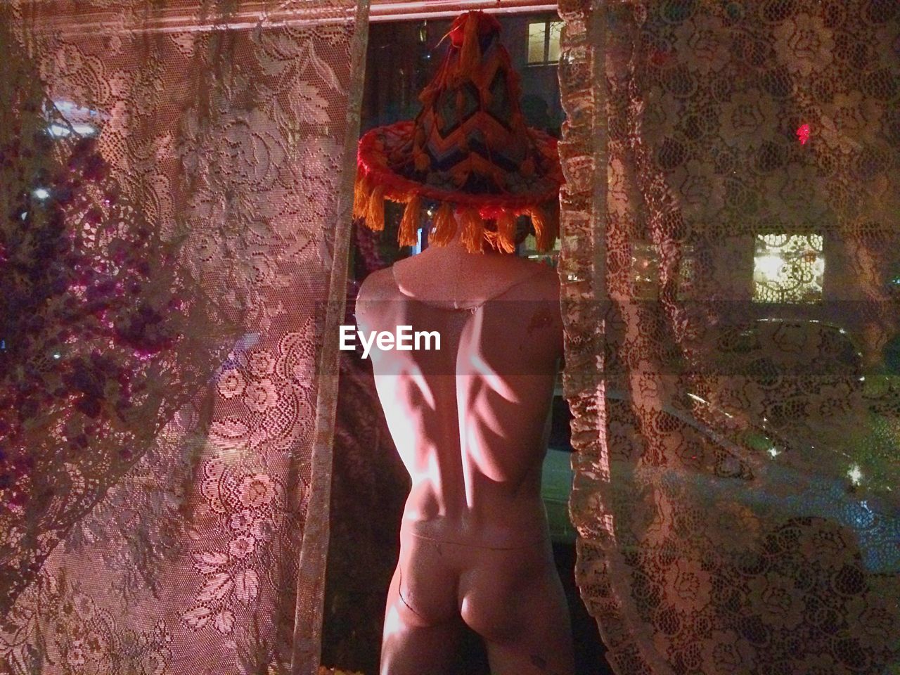 Rear view of naked mannequin with curtains