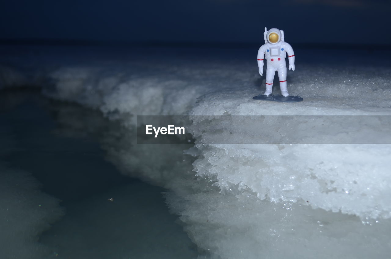 Astronaut figurine on salt at night