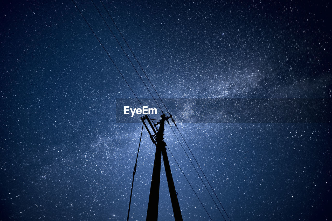 Low angle view of electricity pylon against sky at night