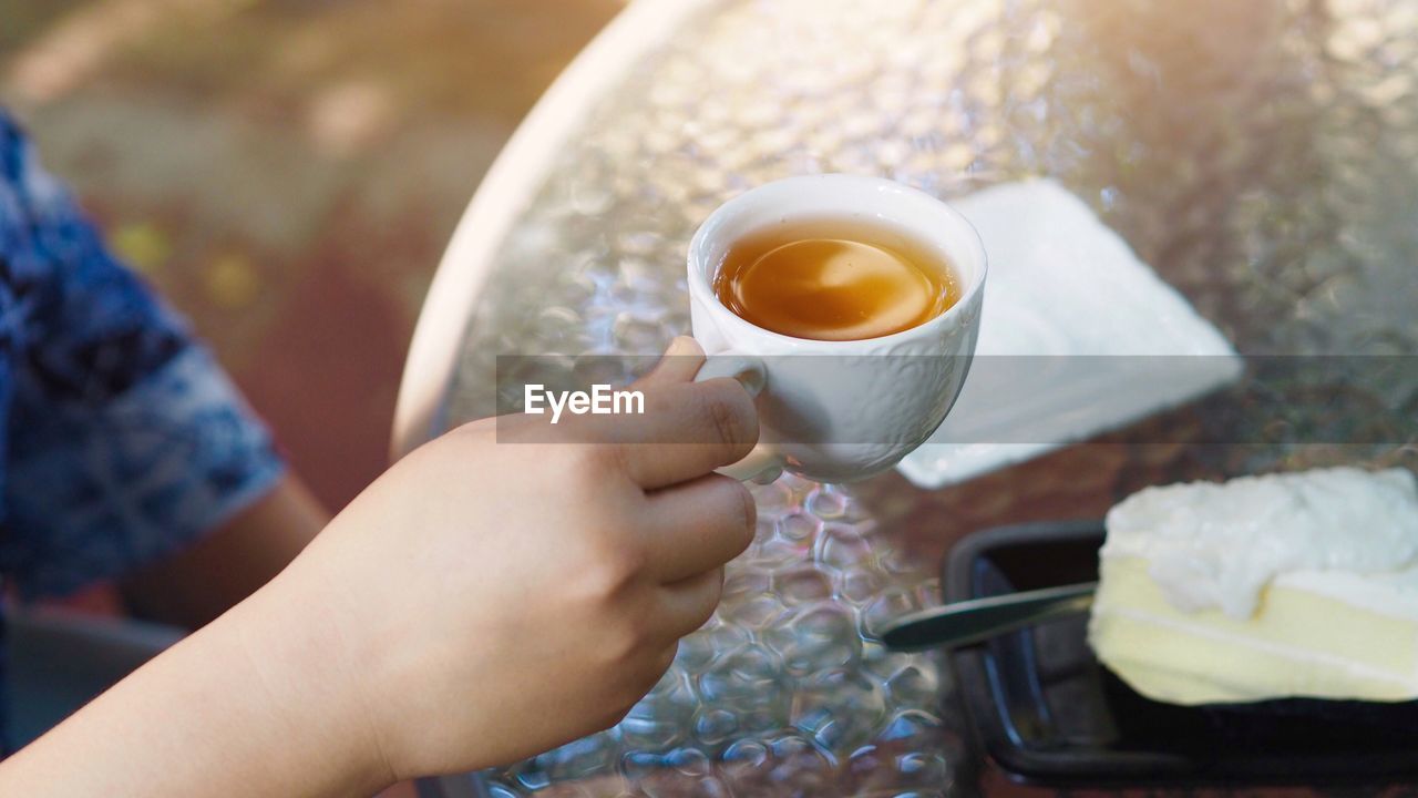 Cropped image of person holding coffee in early morning